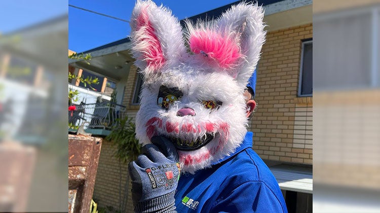 1-800-GOT-JUNK? truck team member holding a scary bunny mask over face