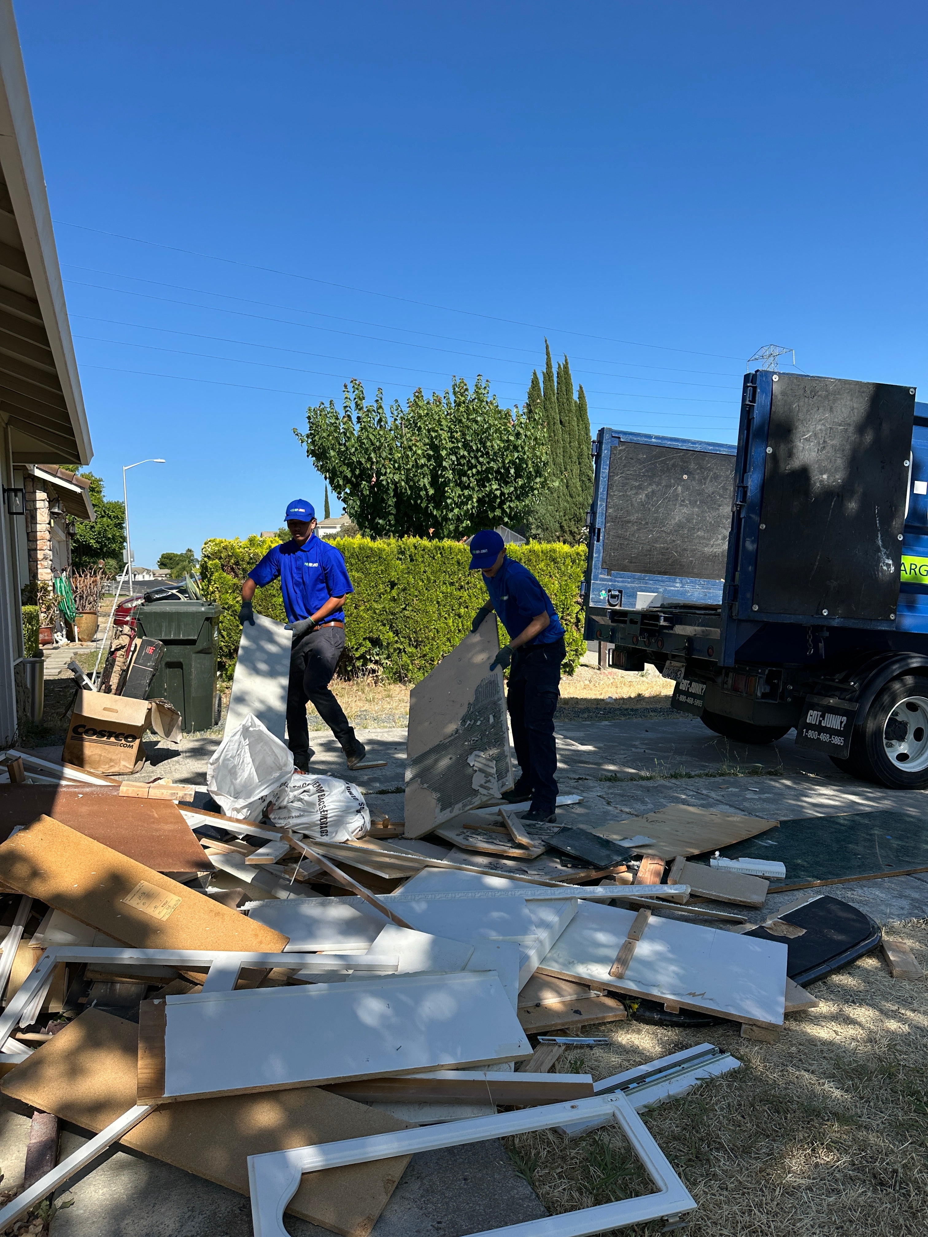 Two 1-800-GOT-JUNK? team members loading kitchen renovation debris into a truck during a junk removal service in Antioch, CA.