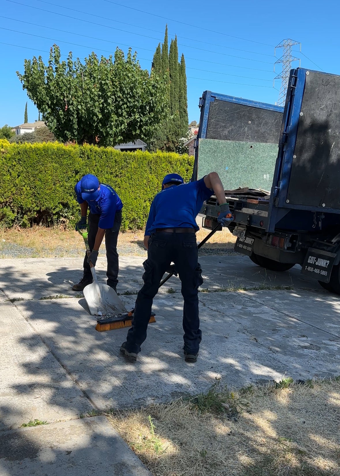 Two 1-800-GOT-JUNK? team members sweeping up debris after completing a junk removal service in Antioch, CA.
