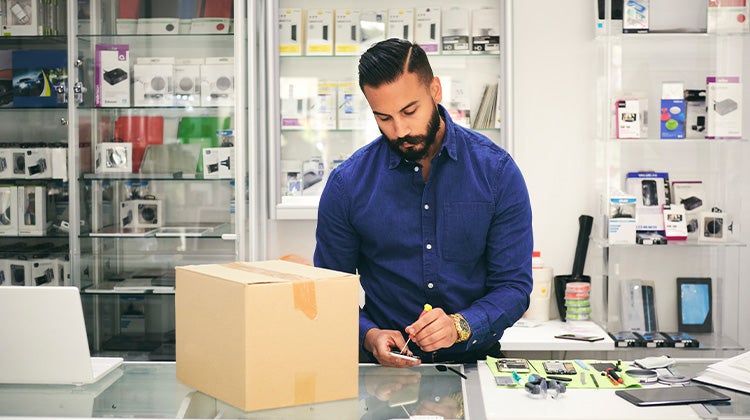 A man packing old phones and electronics in a box for proper disposal