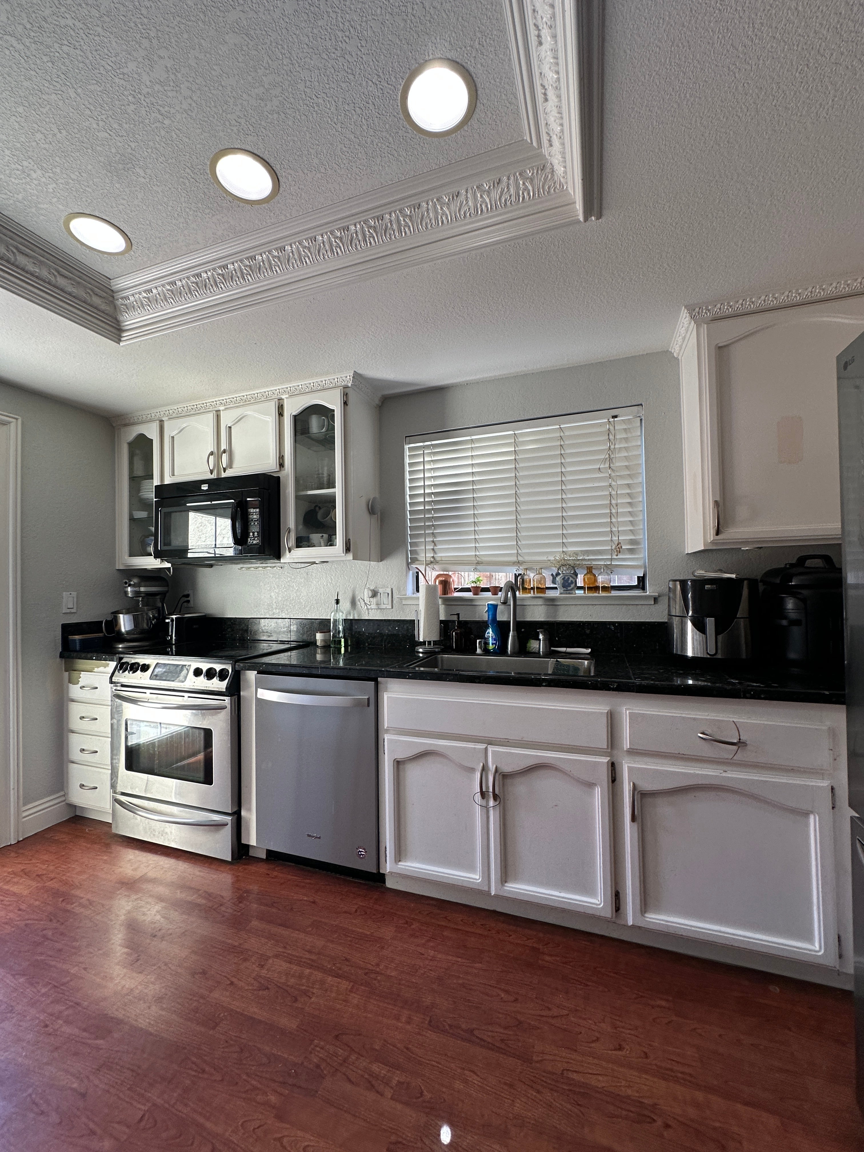 Original kitchen before renovation, showing white cabinets, black countertops, and appliances, in Antioch, CA.