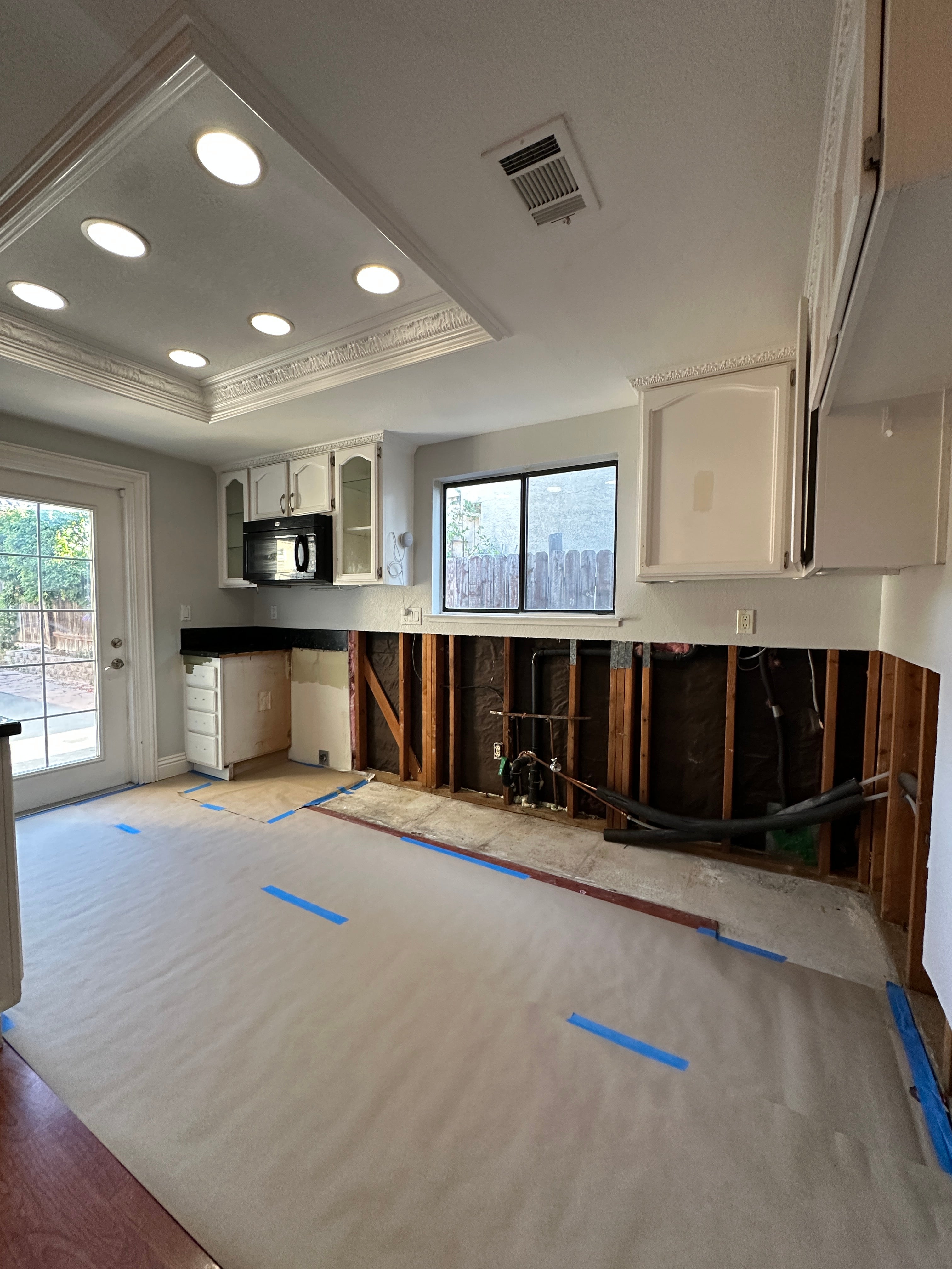 Kitchen interior during renovation in Antioch, CA, showing exposed wall studs where lower cabinets were removed due to mold.