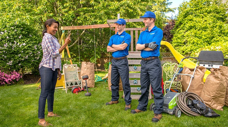 1-800-GOT-JUNK? team with a lawn mower for pick up in front of a customer