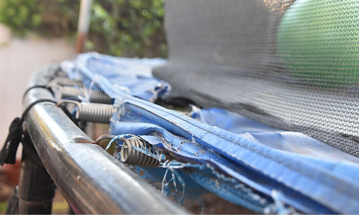 An old trampoline sitting on the curbside for removal and recycling.