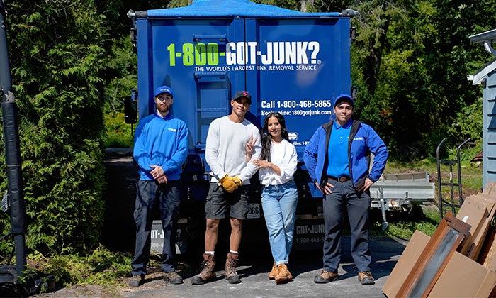 A woman, man and two 1-800-GOT-JUNK? Truck Team Members smiling in front of the truck