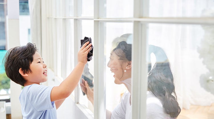 Mother and son cleaning windows together 